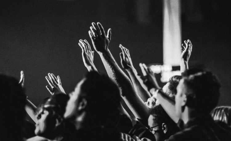 grayscale photo of people raising their hands